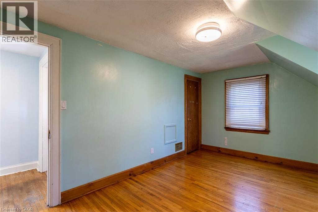 Room featuring wood-finish flooring, light blue walls, and a white ceiling - 17 Thorndale Street N, Hamilton, ON
