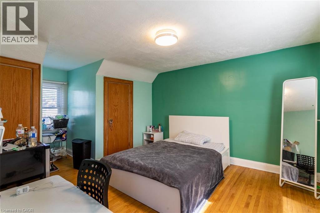 Hardwood flooring throughout featuring a window with blinds, two paneled wooden doors, and a flush mount ceiling light fixture - 17 Thorndale Street N, Hamilton, ON