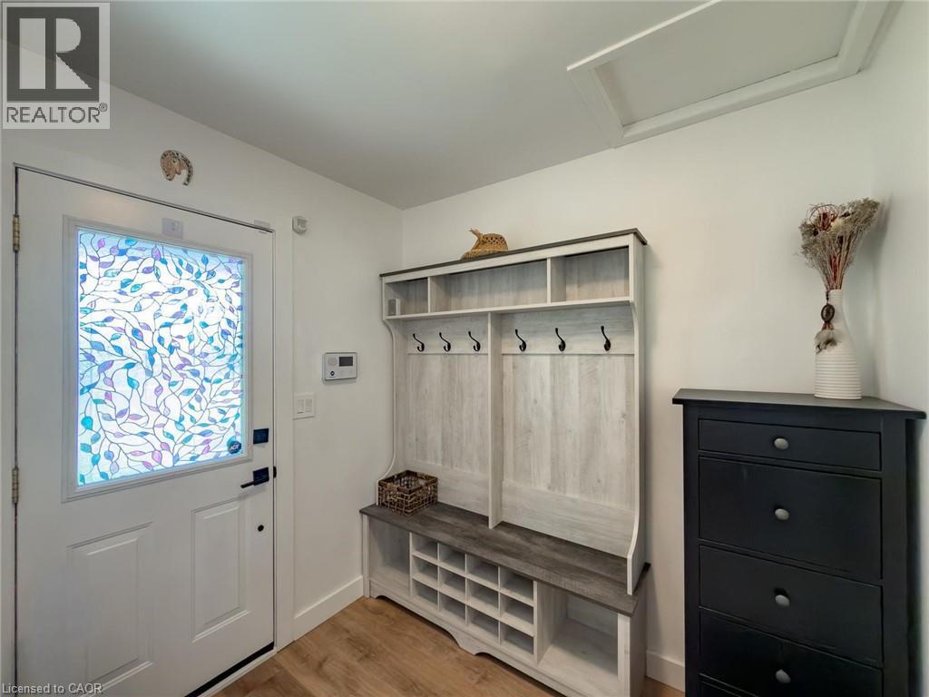 Entryway featuring a white door with decorative glass, wood-finish flooring, and a built-in coat and shoe storage unit - 1324 Bodley Road, Mississauga, ON
