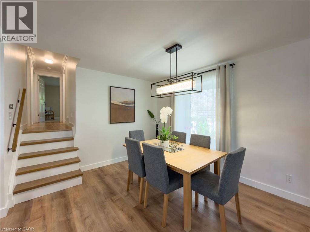 Dining area featuring wood-finish flooring, a rectangular light wood table, and a linear chandelier with a black frame - 1324 Bodley Road, Mississauga, ON
