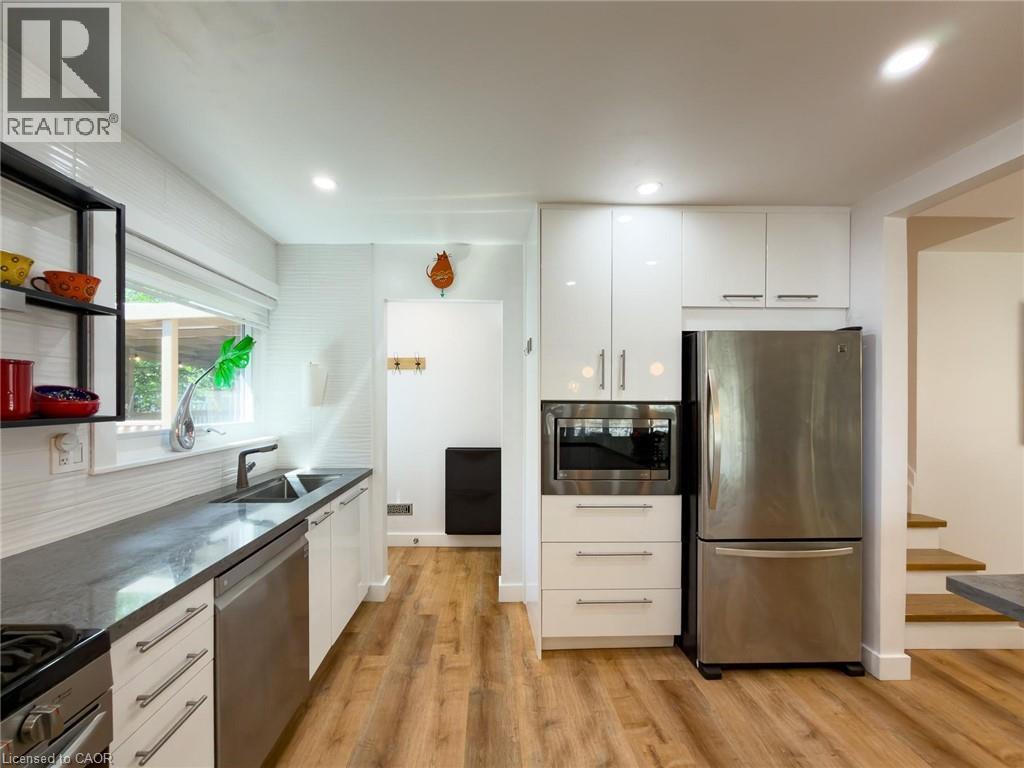 Kitchen with white cabinetry, dark countertops, wood-finish flooring, recessed lighting, and stainless steel appliances - 1324 Bodley Road, Mississauga, ON