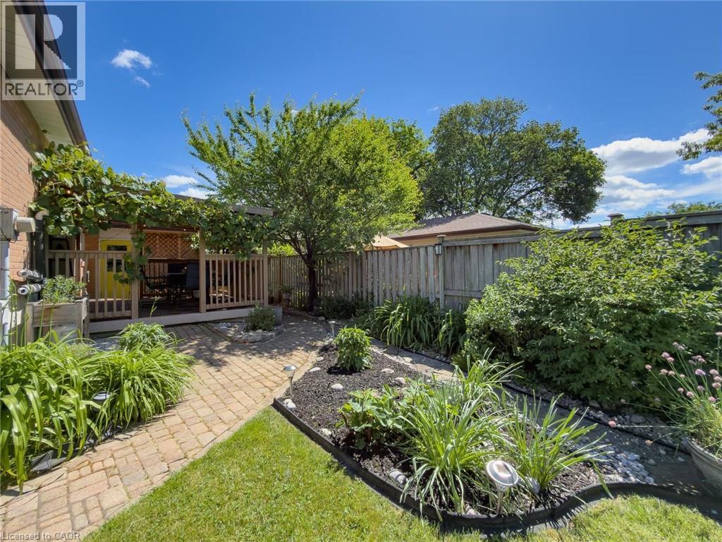 Landscaped backyard featuring a stone paver path, mature plantings, and a wooden deck - 1324 Bodley Road, Mississauga, ON