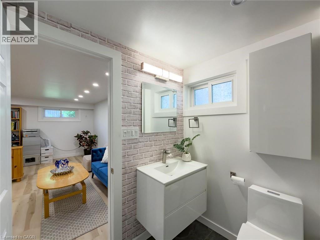 Contemporary bathroom featuring a white vanity with integrated sink, a rectangular mirror, and a frosted window - 1324 Bodley Road, Mississauga, ON
