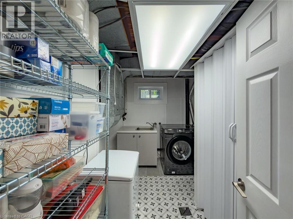 Utility space featuring patterned floor tiles, a built-in wash basin with cabinetry, and a window - 1324 Bodley Road, Mississauga, ON