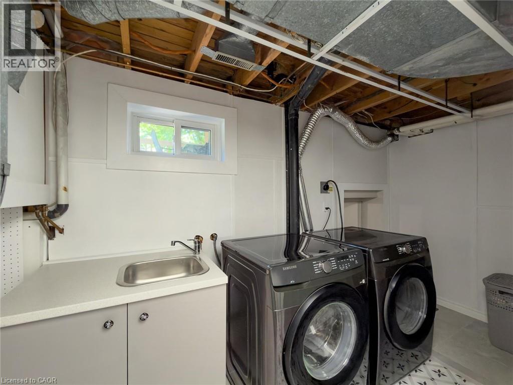 Dedicated laundry area featuring a utility sink, light gray base cabinetry, and a white countertop - 1324 Bodley Road, Mississauga, ON