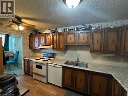Kitchen featuring wood-finish cabinetry, laminate countertops, and a double basin sink -
