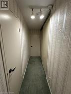 Hallway featuring patterned wallpaper, track lighting, and carpet flooring -