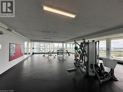Fitness facility with expansive floor-to-ceiling windows, dark resilient flooring, and multiple fluorescent light fixtures -