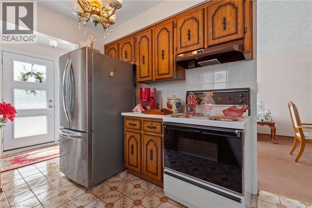 Kitchen area featuring warm wood cabinetry, a white tile backsplash, and patterned floor tiles. - 202 Ray Street N, Hamilton, ON - Indoor Photo Showing Kitchen