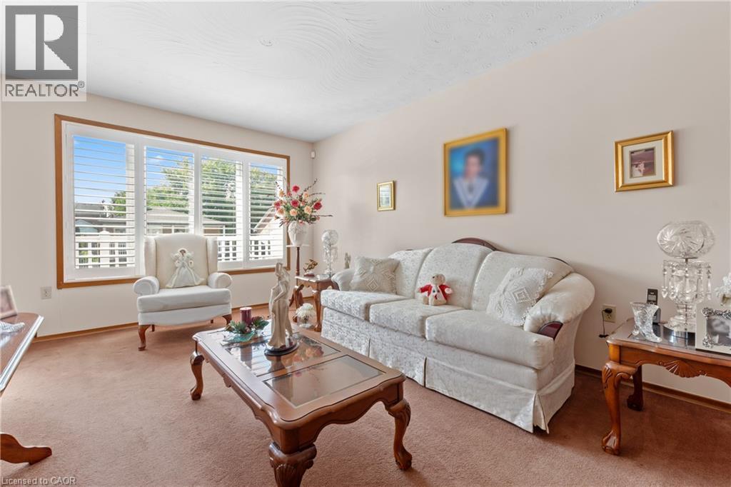 Spacious living area featuring a large window with white plantation shutters, light-toned walls, and wood trim details. - 202 Ray Street N, Hamilton, ON - Indoor Photo Showing Living Room