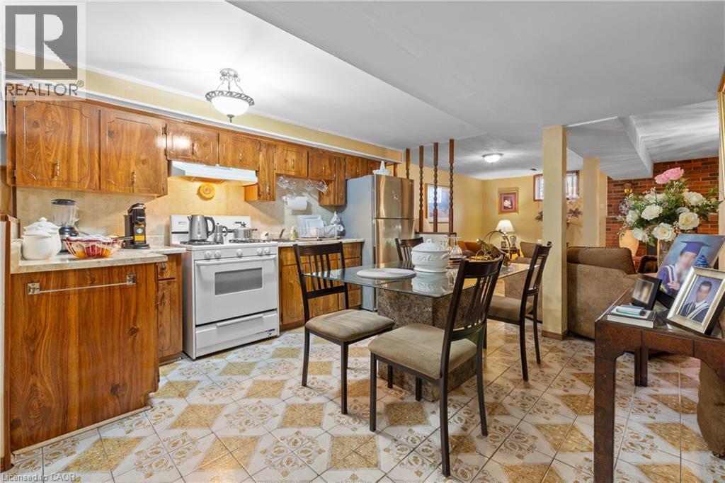 Kitchen area featuring wood-finish cabinetry, a white gas range, and a stainless steel refrigerator. - 202 Ray Street N, Hamilton, ON - Indoor Photo Showing Kitchen