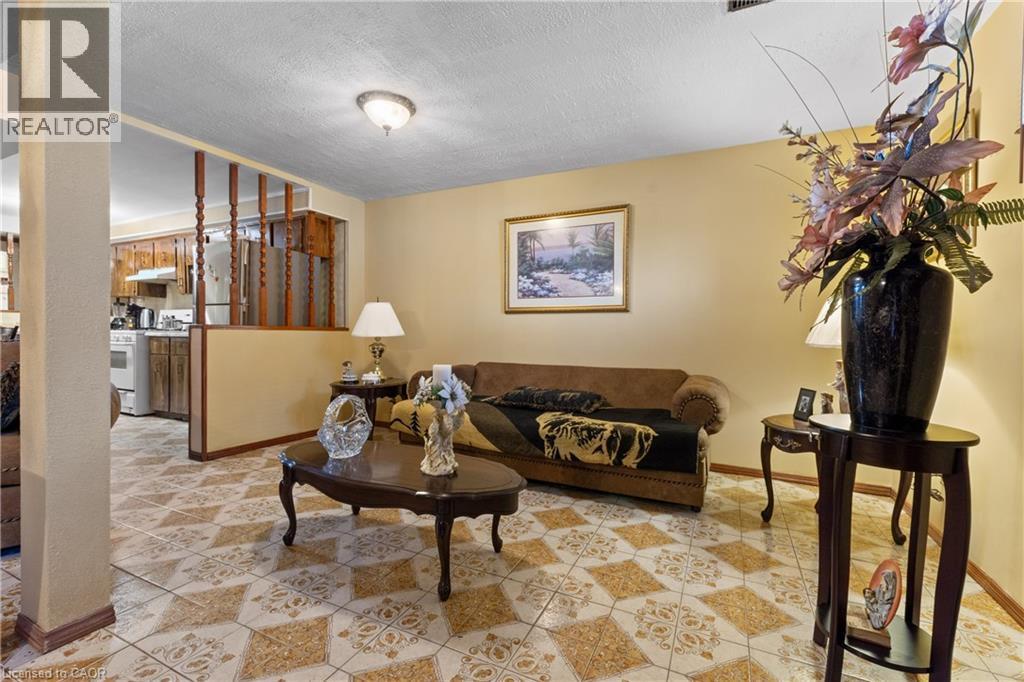 Living area featuring patterned floor tile, cream-toned walls, and a partial decorative wood partition. - 202 Ray Street N, Hamilton, ON - Indoor