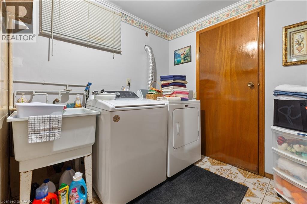 Dedicated laundry area featuring a utility sink, a window with blinds, and durable tile flooring. - 202 Ray Street N, Hamilton, ON - Indoor Photo Showing Laundry Room