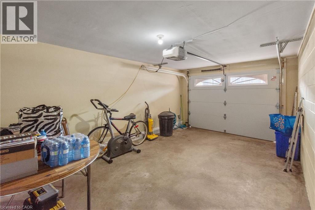Attached garage featuring a concrete floor, painted block wall, and an overhead garage door with arched window panels. - 202 Ray Street N, Hamilton, ON - Indoor Photo Showing Garage