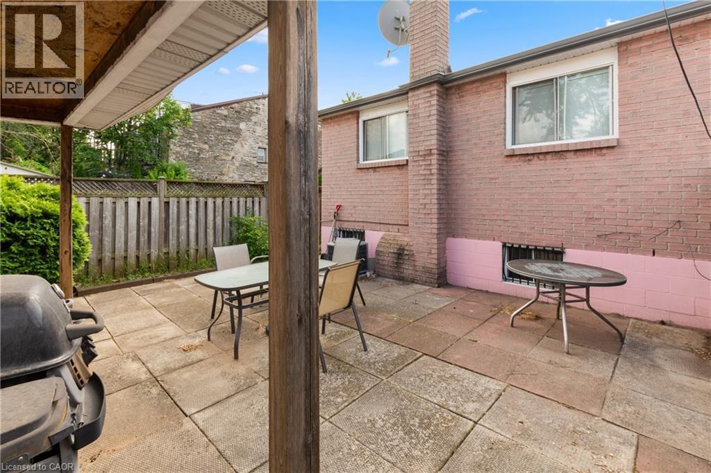 Patio area featuring concrete paver flooring, a partial wood pergola structure, and a wood privacy fence. - 202 Ray Street N, Hamilton, ON - Outdoor With Exterior