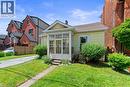 Yellow-sided residence featuring a screened-in front porch, a gabled roofline, and a paved driveway. - 193 Locke Street N, Hamilton, ON  - Outdoor With Facade 
