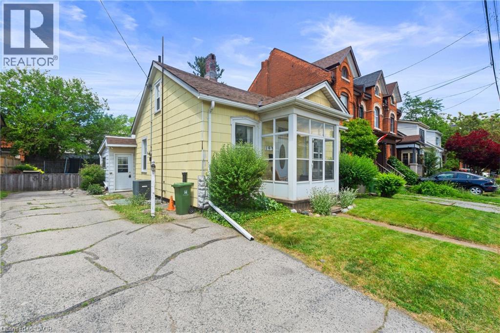 Yellow-sided residence featuring a screened-in front porch, a gabled roofline, and a paved driveway. - 193 Locke Street N, Hamilton, ON - Outdoor