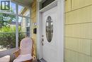 Entryway featuring a white door with decorative oval glass, brass hardware, and contrasting yellow shingle siding. - 193 Locke Street N, Hamilton, ON  -  With Exterior 