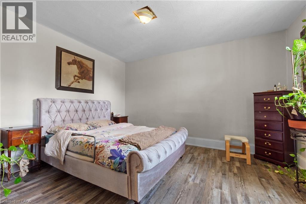 Neutral tone walls with wood-finish flooring and a ceiling-mounted light fixture. - 193 Locke Street N, Hamilton, ON - Indoor Photo Showing Bedroom