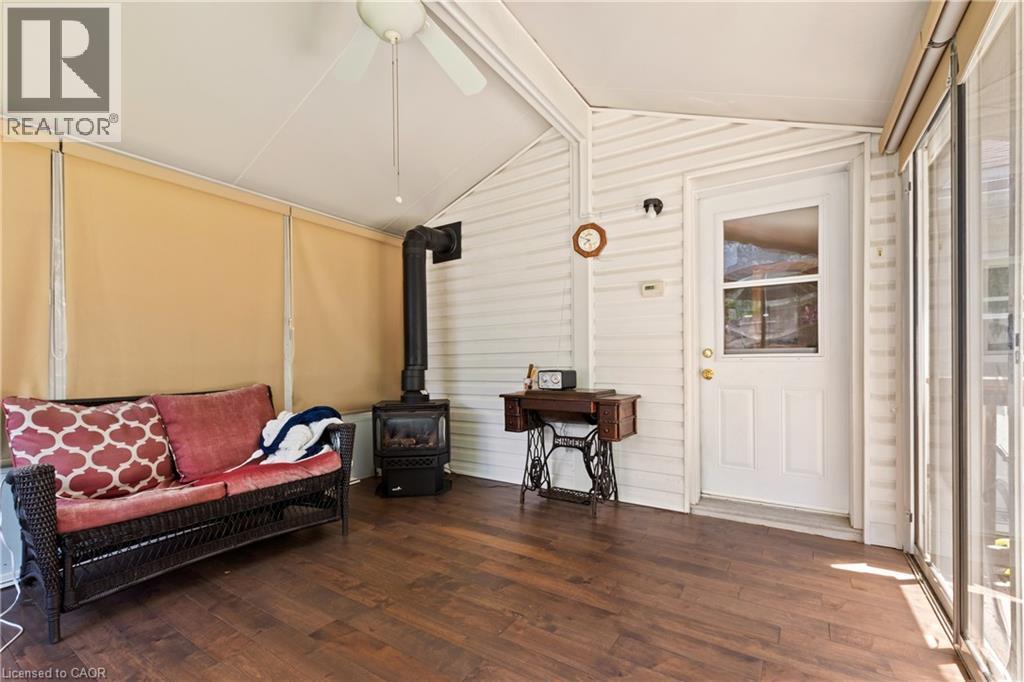 Enclosed sunroom featuring wood-finish flooring, a ceiling fan, and a built-in wood-burning stove. - 193 Locke Street N, Hamilton, ON - Indoor Photo Showing Other Room