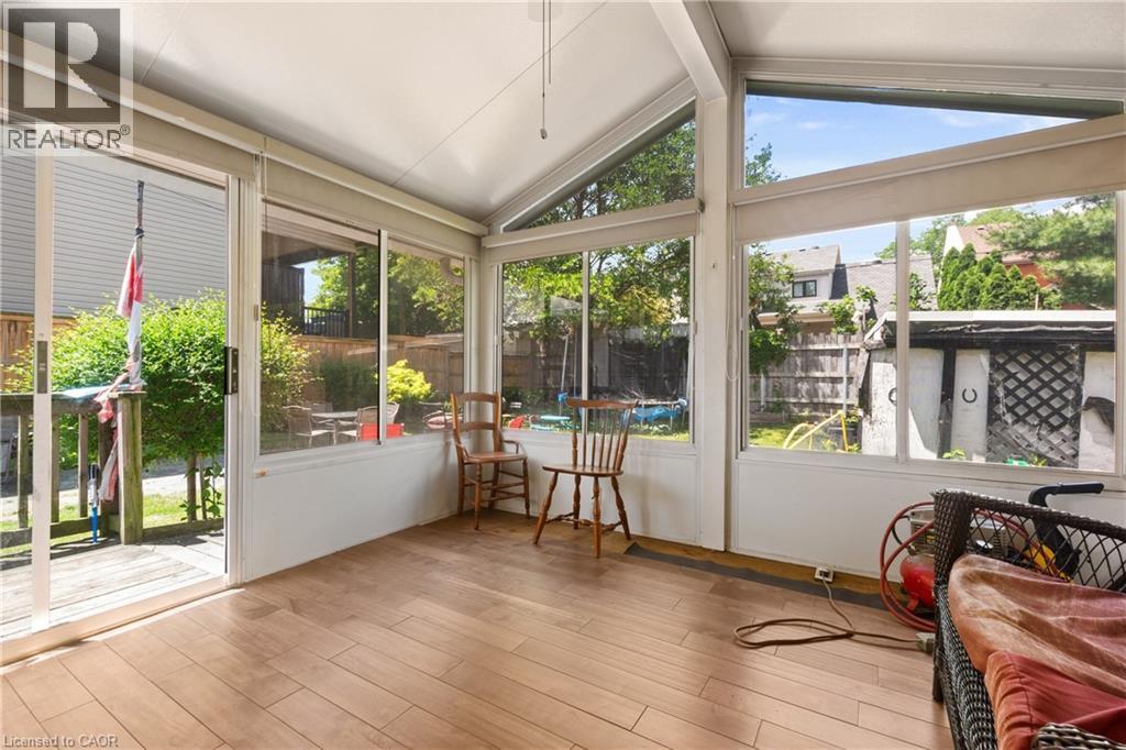 Sunroom featuring extensive window-lines, vaulted ceiling, wood-finish flooring, and sliding glass door access to an exterior deck. - 193 Locke Street N, Hamilton, ON - Photo Showing Other Room