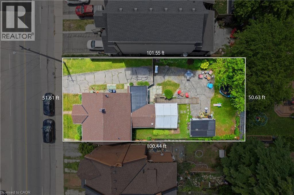 Aerial view showcasing the property with a brown shingled roof, extensive paved driveway, and established trees, with lot measurements. - 193 Locke Street N, Hamilton, ON -