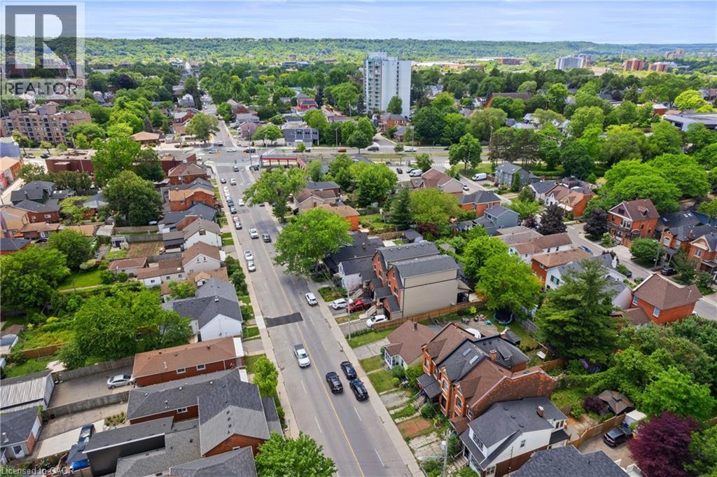Aerial perspective showcasing a tree-lined residential street with various architectural styles, including brick and siding exteriors, surrounded by mature greenery - 193 Locke Street N, Hamilton, ON - Outdoor With Deck Patio Veranda With View