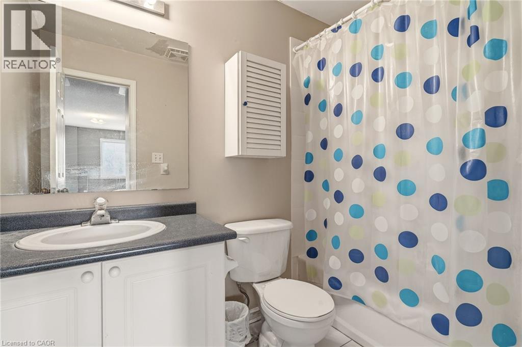 Bathroom featuring a white vanity with an integrated sink, dark countertop, and an overhead light fixture - 4413 Peter Drive, Burlington, ON