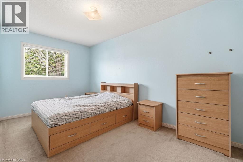 Carpeted bedroom featuring light blue walls, a window with horizontal blinds, and a flush-mount ceiling light fixture - 4413 Peter Drive, Burlington, ON