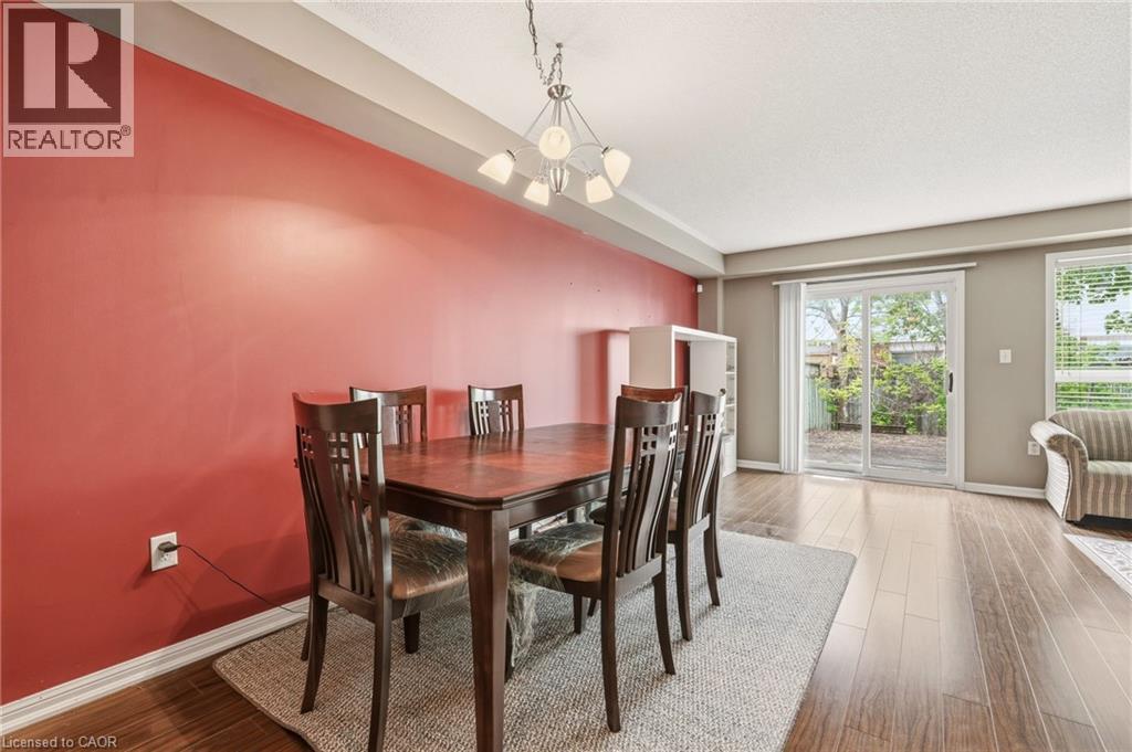 Bright interior space featuring a red accent wall, wood-finish flooring, and a contemporary chandelier - 4413 Peter Drive, Burlington, ON