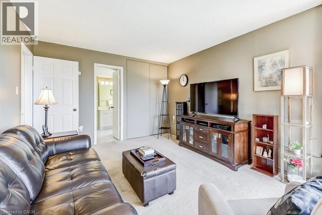 Carpeted living area featuring a neutral wall palette, white trim, and a white six-panel door - 1201 North Shore Boulevard E Unit# 706, Burlington, ON - Indoor Photo Showing Living Room