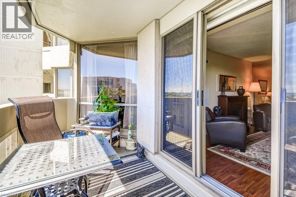 Private balcony featuring a painted concrete floor, striped area rug, and full-height glass sliding door - 1201 North Shore Boulevard E Unit# 706, Burlington, ON -