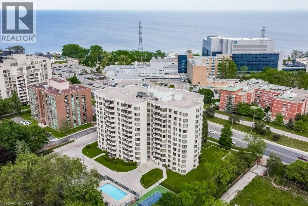 Multi-story residential building featuring a light-colored facade and numerous balconies - 1201 North Shore Boulevard E Unit# 706, Burlington, ON - Outdoor With Body Of Water With View