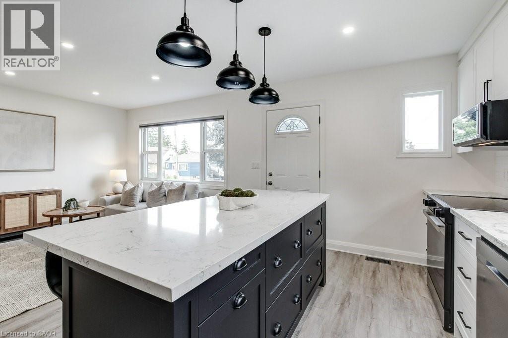 Kitchen island with a light-toned countertop, black cabinetry, and three pendant light fixtures - 202 Erindale Avenue, Hamilton, ON