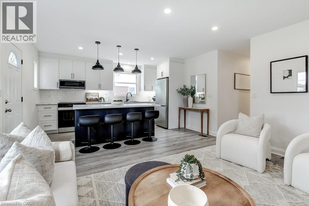 Open-concept living space featuring wood-finish flooring, recessed lighting, and a kitchen island with seating - 202 Erindale Avenue, Hamilton, ON