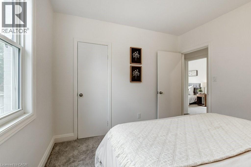 Bright interior space featuring white walls, gray carpet, a white door with a round doorknob, and a white-framed window - 202 Erindale Avenue, Hamilton, ON
