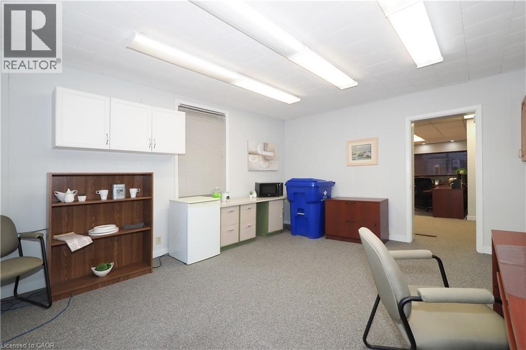 Interior room featuring light gray carpeting, white walls, and a drop ceiling with fluorescent lighting - 731 King Street E, Cambridge, ON