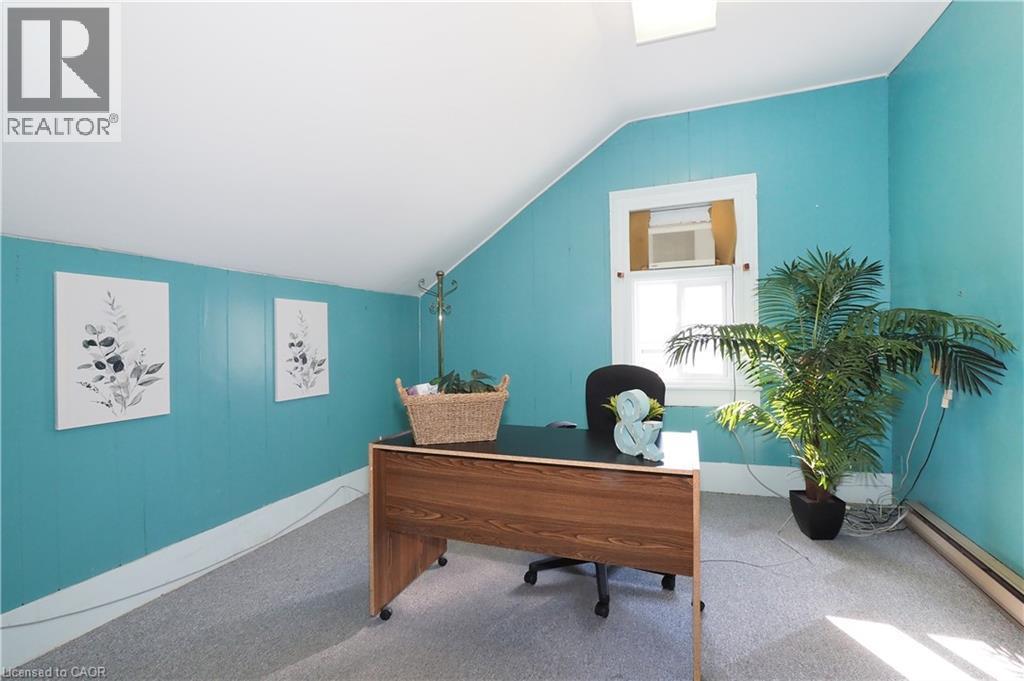 Room with sloped ceilings and light blue paneling, featuring a built-in window unit, white trim, and light gray carpeting - 731 King Street E, Cambridge, ON