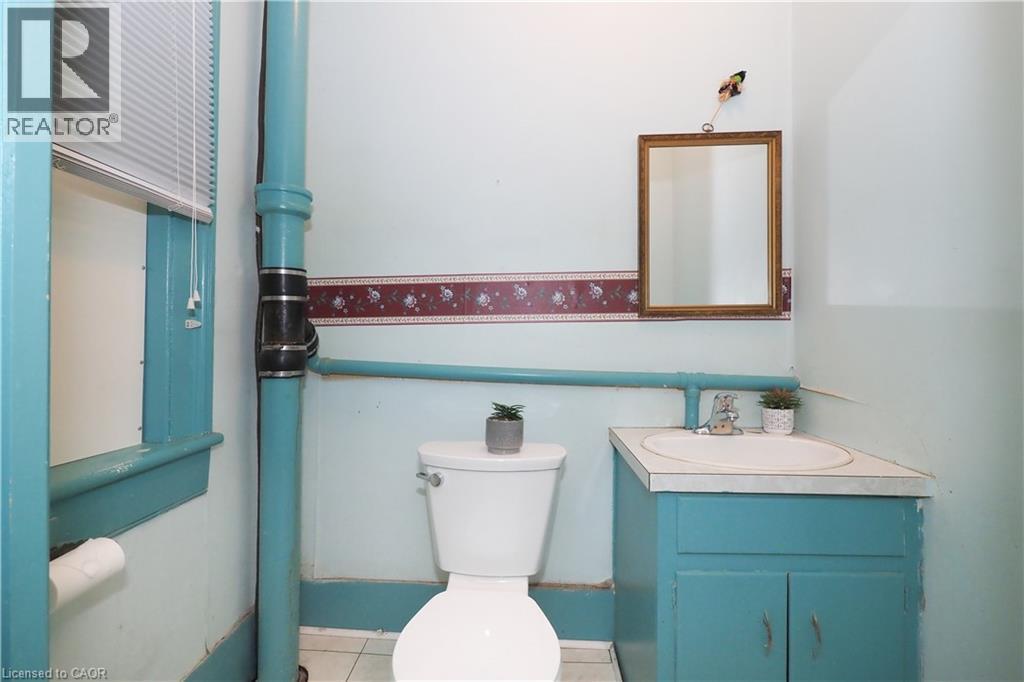 Bathroom featuring a corner vanity with an integrated sink, a wall-mounted mirror, and a window with blinds - 731 King Street E, Cambridge, ON