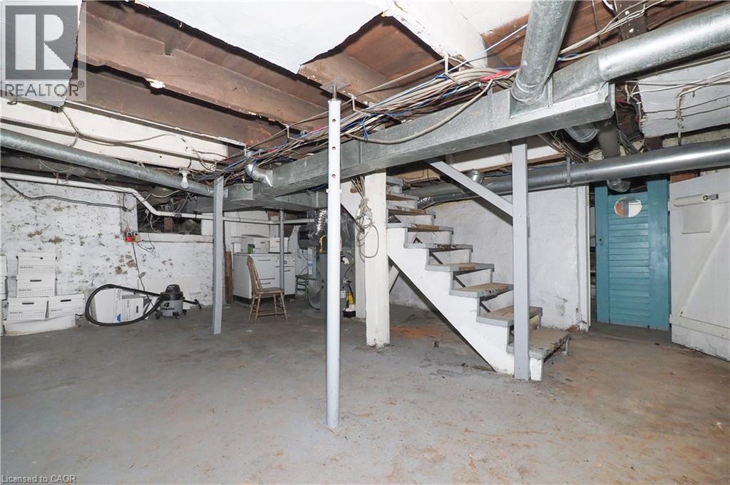Unfinished basement featuring concrete flooring, exposed ceiling joists, and a partial staircase - 731 King Street E, Cambridge, ON