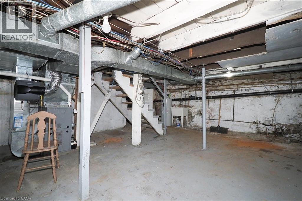 Unfinished basement space featuring exposed ceiling joists, concrete flooring, utility sink, and visible HVAC ductwork - 731 King Street E, Cambridge, ON