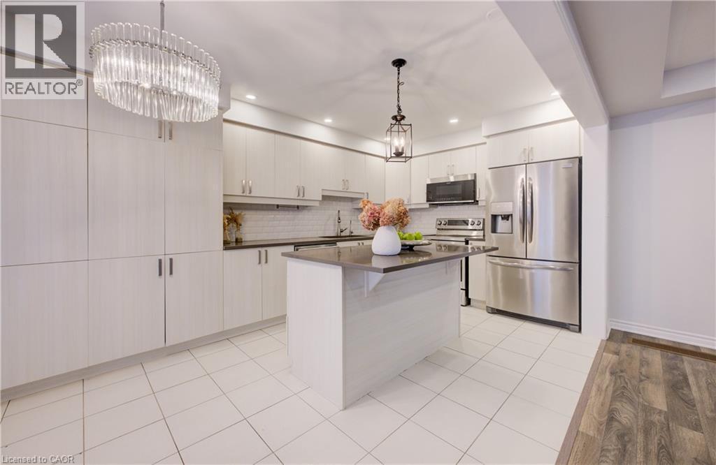 Kitchen featuring stainless steel appliances, a center island, suspended lighting, a kitchen breakfast bar, and light wood-style flooring - 302 Jean Landing, Milton, ON