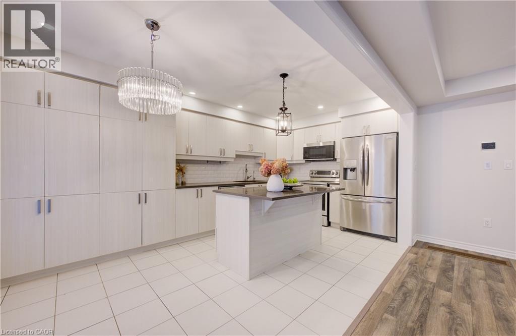 Kitchen with stainless steel appliances, a center island, light wood-style flooring, a kitchen breakfast bar, and suspended lighting - 302 Jean Landing, Milton, ON
