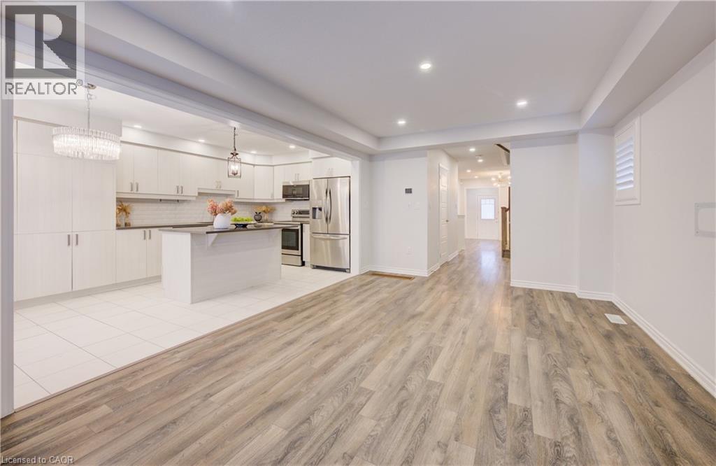 Kitchen with stainless steel appliances, dark countertops, a center island, light wood-style flooring, and open floor plan - 302 Jean Landing, Milton, ON