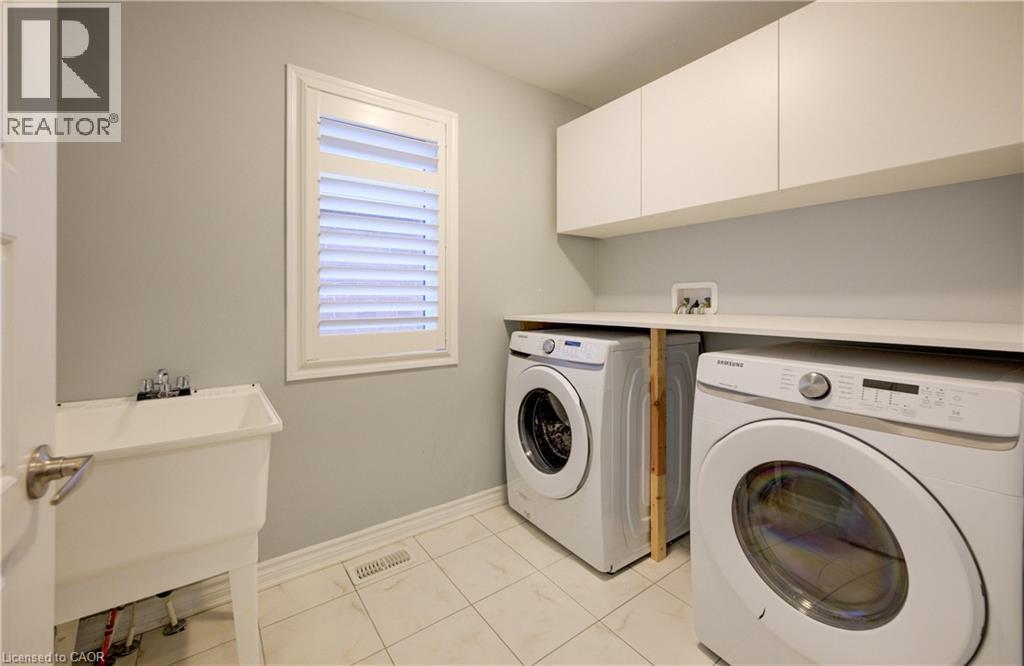 Laundry room with washer and clothes dryer, light tile patterned flooring, and cabinet space - 302 Jean Landing, Milton, ON