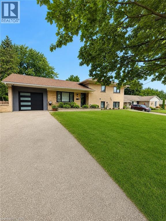 Brick exterior with a modern garage door - 33 Tyrell Street, Simcoe, ON - Outdoor With Facade