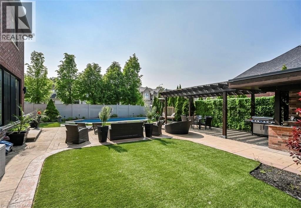 Expansive backyard featuring a swimming pool, stamped concrete patio, artificial turf, a pergola, and an outdoor kitchen area with a built-in grill - 137 Diiorio Circle, Ancaster, ON