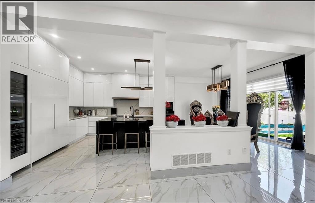 Contemporary kitchen featuring glossy white cabinetry, a large black island with seating, a built-in wine refrigerator, and integrated appliances - 137 Diiorio Circle, Ancaster, ON