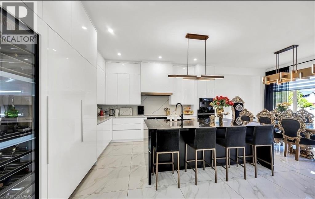 Contemporary kitchen featuring a large black island with seating, white high-gloss cabinetry, and a built-in wine refrigerator - 137 Diiorio Circle, Ancaster, ON