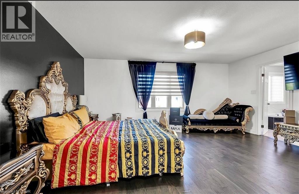 Spacious room featuring dark wood-finish flooring, a contemporary semi-flush mount light fixture, and a window with blinds and dark curtains - 137 Diiorio Circle, Ancaster, ON